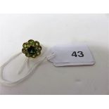 A gold ring stamped 18ct with a large central flower head of green stones, weight approx 5.5g.