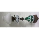 Victorian brass and glass oil lamp, with the top half with green leaves and with a white background,