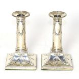 A pair of late Victorian silver candlesticks of George III style, London, 1900, decorated with