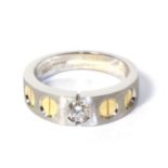 An 18 carat two colour gold solitaire diamond ring, a round brilliant cut diamond inset to a brushed