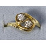 A diamond two stone ring, round brilliant cut diamonds in a bypass setting, stated diamond weight