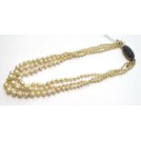 A triple strand cultured pearl necklace, graduated cultured pearls knotted to a sapphire set