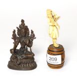 A bronze Tibetan Buddha figure and a late 19th century ivory trumpeter figure, standing on a barrel
