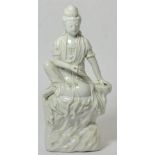 A Chinese Blanc de Chine Figure of Guanyin, Qing Dynasty, sitting on a rocky outcrop, 50cm high