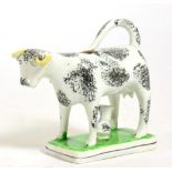 A Pearlware Cow Creamer, 19th century, the standing beast with black sponged markings, a calf at its