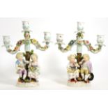 A Pair of Sitzendorf Porcelain Figural Candelabra, circa 1900, with three lights on foliate scroll