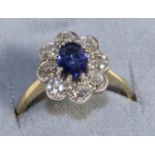 A Sapphire and Diamond Cluster Ring, an oval cut sapphire in a claw setting within a border of old