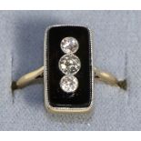 An Art Deco Onyx and Diamond Ring, three graduated old cut diamonds in milgrain settings to a