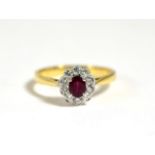 A Ruby and Diamond Cluster Ring, a round cut ruby in a claw setting, within a border of round