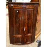 A George III Mahogany and Inlaid Bowfront Hanging Corner Cupboard, early 19th century, with dentil