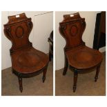 A Pair of Late Regency Mahogany Hall Chairs, early 19th century, with scrolled top rails and oval