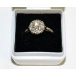 A diamond cluster ring, a round brilliant cut diamond within a border of illusion set eight-cut