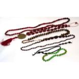 Three red plastic bead necklaces, a faceted green glass necklace, a bovine horn bead necklace and