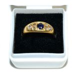 An 18 carat gold sapphire and diamond ring, a round cut sapphire spaced by groups of old cut