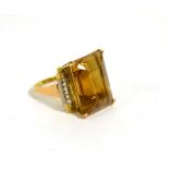 A citrine ring, an octagonal cut citrine in a double claw setting, to fancy scroll shoulders, finger