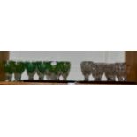 A shelf of clear and green glass drinking glasses