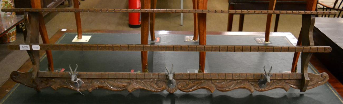 A carved wooden coat rack with patinated metal springbok head hangers