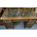 An Edwardian oak desk, early 20th century, with green leather top, with six drawers and a cupboard