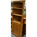 An Ercol light elm corner cupboard