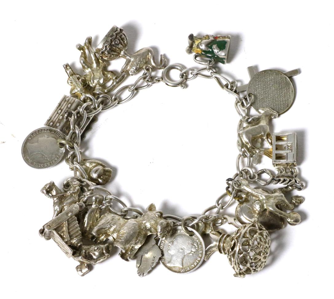 A charm bracelet, with 23 various silver and white metal charms, including an enamelled Toby jug,