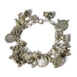 A charm bracelet, with 23 various silver and white metal charms, including an enamelled Toby jug,