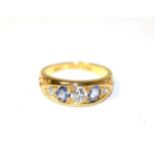 An 18 carat gold sapphire and diamond ring, three graduated old cut diamonds, spaced by oval cut