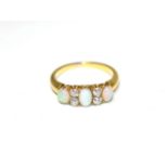 An opal and diamond ring, three oval cabochon opals, spaced by pairs of old cut diamonds, total