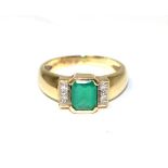 A 9 carat gold synthetic emerald and a diamond ring, an octagonal cut emerald in a rubbed over