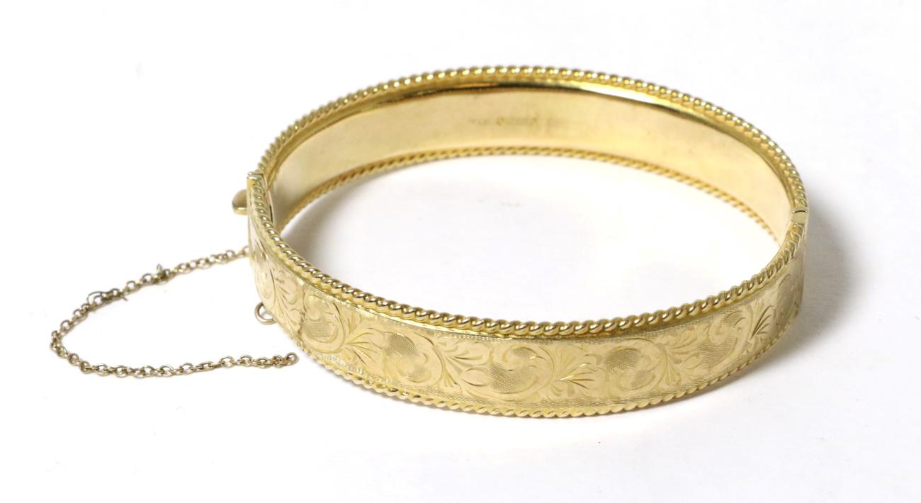 A 9 carat gold hinge opening bangle, with chased decoration and rope border, 6cm by 5.5cm inner