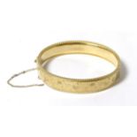 A 9 carat gold hinge opening bangle, with chased decoration and rope border, 6cm by 5.5cm inner