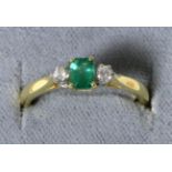 An 18 carat gold emerald and diamond three stone ring, an octagonal cut emerald, spaced by round