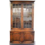 A Reproduction Oak Bookcase, with a bold cornice above glazed doors enclosing three adjustable