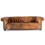 A Chesterfield Sofa, upholstered in worn brown buttoned leather, with rounded back support, arms and