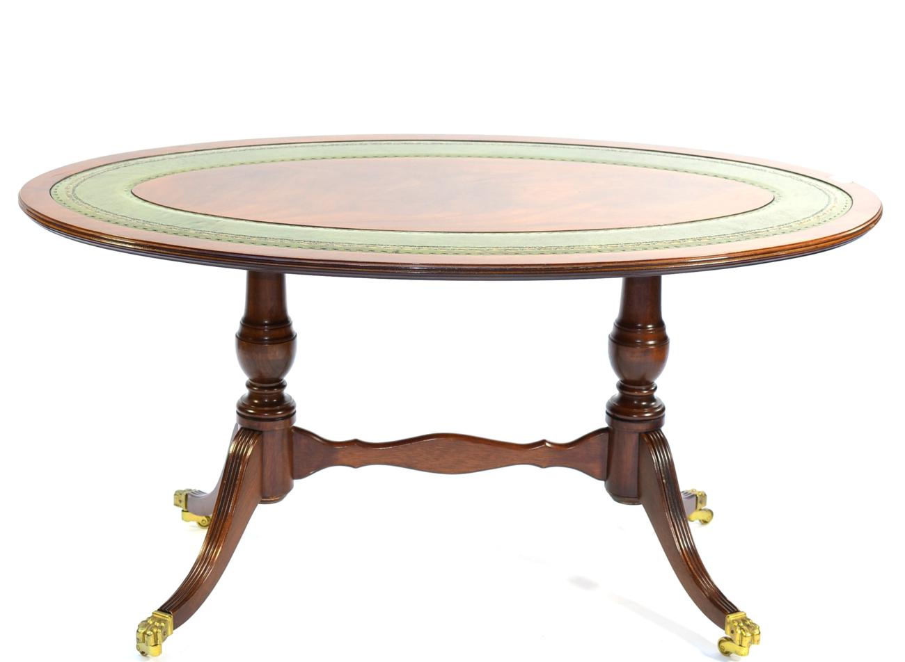 A Reproduction Mahogany Oval Coffee Table, in Regency style, with a green and gilt leather top,