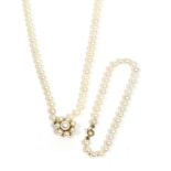 A cultured pearl necklace' two stands of uniform cultured pearls, knotted to a 14 carat gold pearl