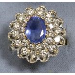 A 9 carat gold sapphire and diamond cluster ring, an oval cut sapphire in a claw setting within a