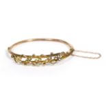 A seed pearl bangle, the crossover front with a motif of seed pearl set trailing vines, to a plain