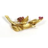 A ruby spray brooch, clusters of round cut rubies to textured leaves, measures 4.3cm by 1.5cm not