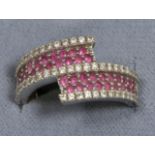 An 18 carat white gold ruby and diamond crossover ring, two rows of round cut rubies between rows of