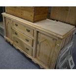 A reproduction pine sideboard with three central drawers and two side doors