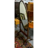 An oval mahogany cheval mirror on cabriole supports, with lion paw feet