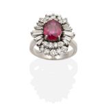 A Ruby and Diamond Cluster Ring, an oval cut ruby in a claw setting, within a two tier border of