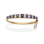 A Victorian Sapphire and Diamond Bangle, nine graduated oval cut sapphires, spaced by pairs of