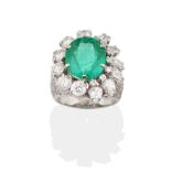 An 18 Carat White Gold Emerald and Diamond Cluster Ring, an oval cut emerald in a claw setting,