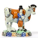A Yorkshire Prattware Cow Group, circa 1800, modelled as a cowherd wearing a top hat, standing