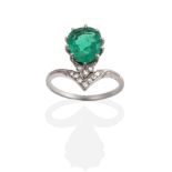 A Belle Epoque Emerald and Diamond Ring, a pear cut emerald in a claw setting, above an eight-cut