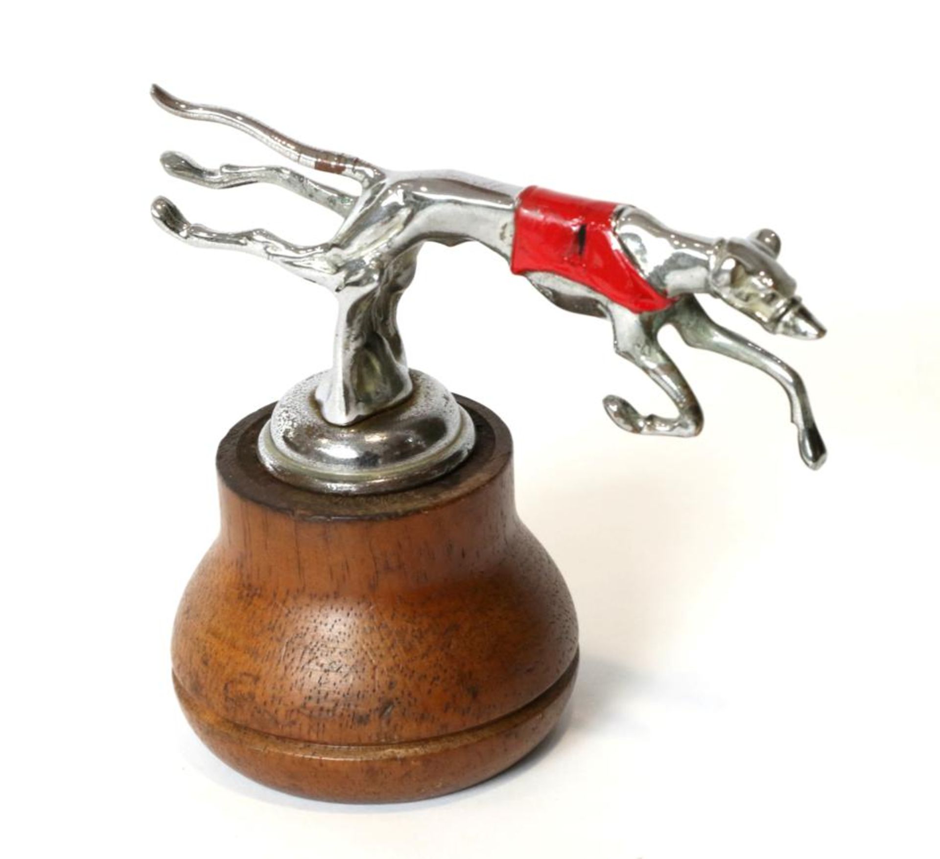 A 1930s Mascot of a Greyhound Leaping Over a Fence, chrome plated wuth red race coat display base