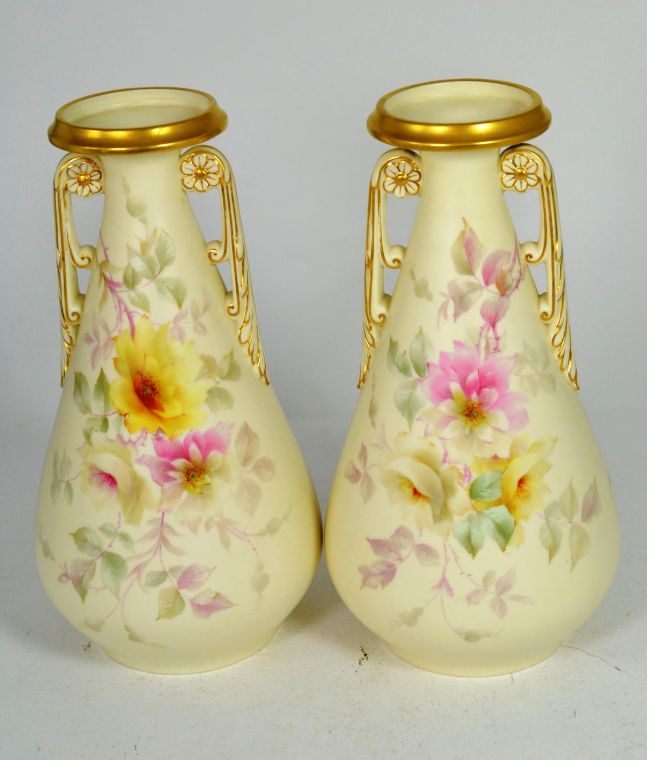 A pair of Royal Worcester China Works floral painted twin handled gilt highlighted vases, 26cm