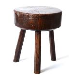 A 19th Century Primitive Oak Stool or Chopping Block, of trunk form raised on three chamfered