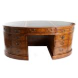 A Walnut Oval Shaped Desk, modern, with green and gilt leather writing surface, with an
